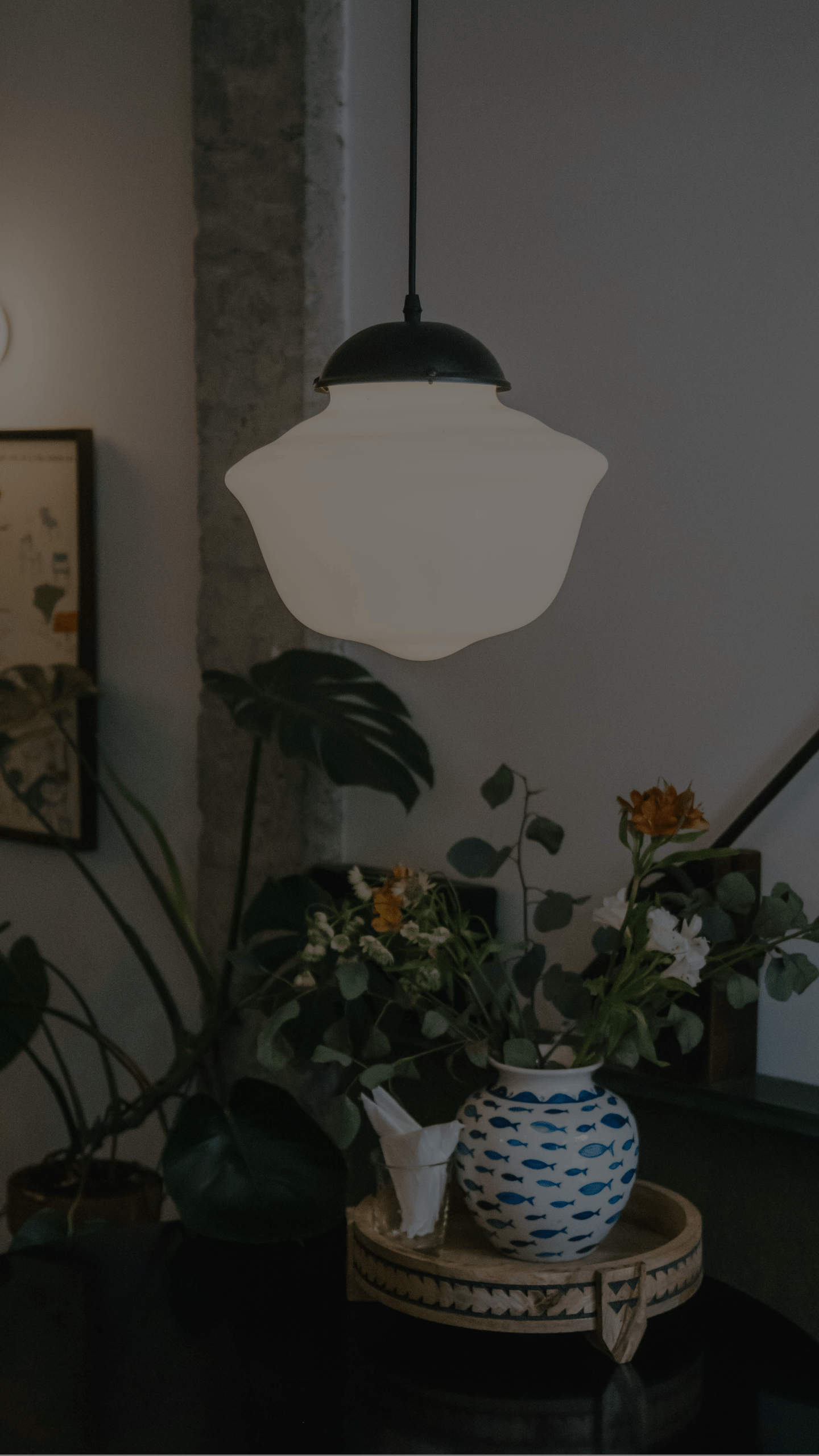 A pendant light hanging over a table with a vase of flowers